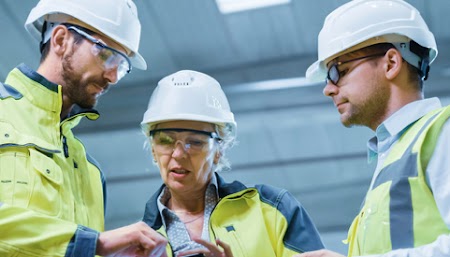Engineers in safety gear reviewing plans